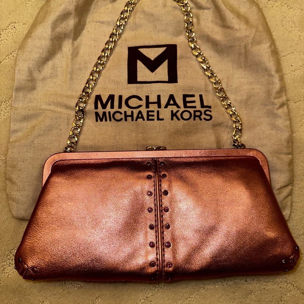 A pink silver clutch with shoulder chain and the dust back Michael Kors.